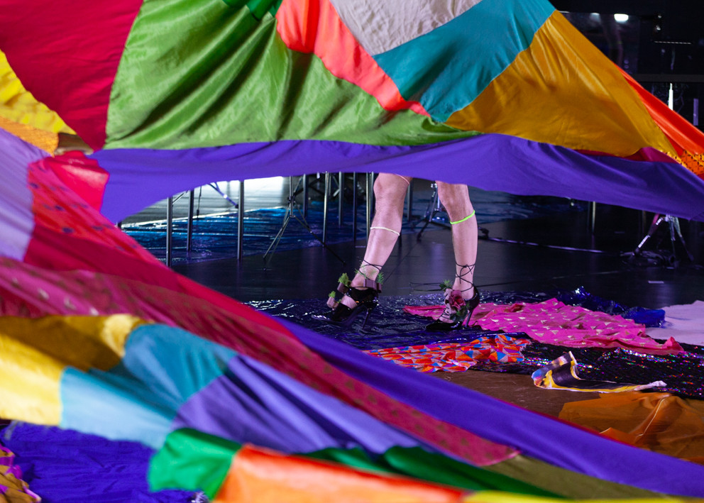 legs in high heels behind colored fabric on stage